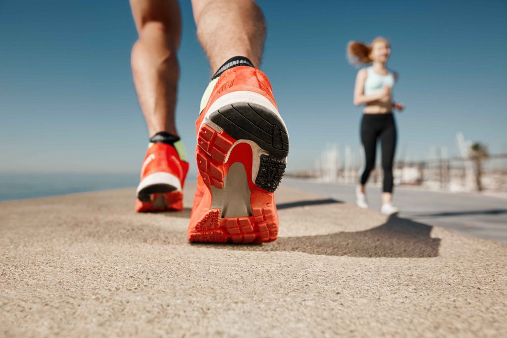 Pelari menggunakan sepatu running dengan outsole kuat di lintasan beton luar ruangan.